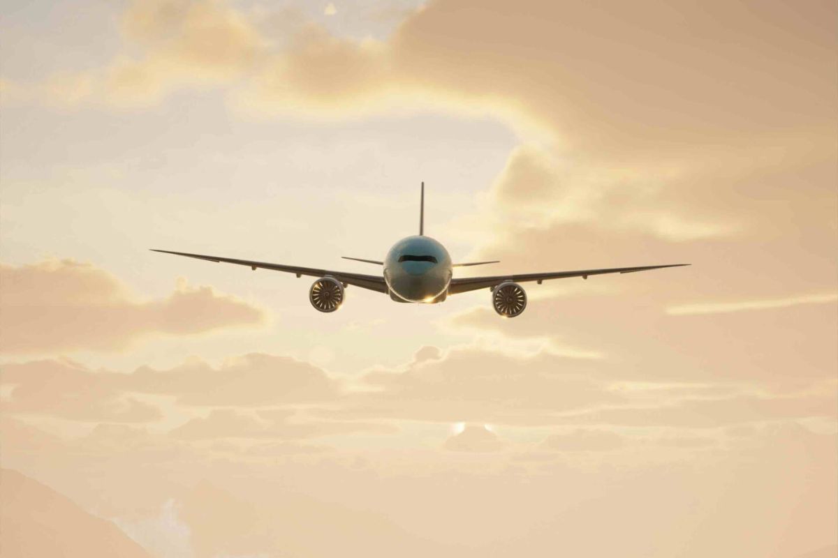 Front view of plane landing with clouds and a setting sun behind